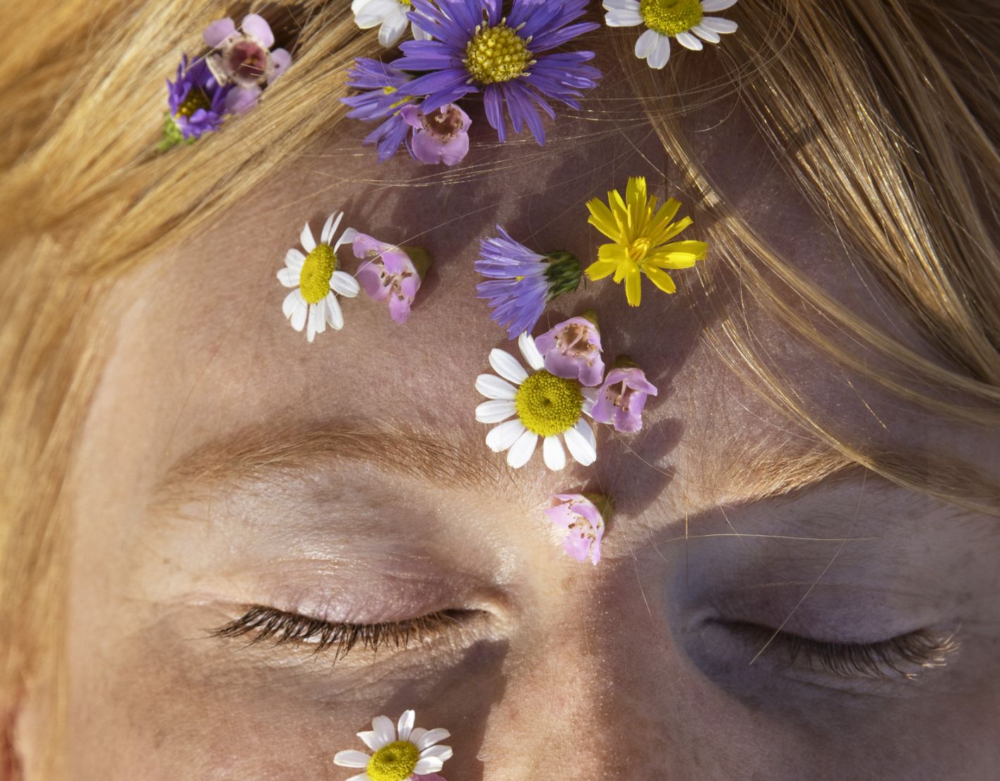 Jeune femme sereine avec des fleurs sur le visage.