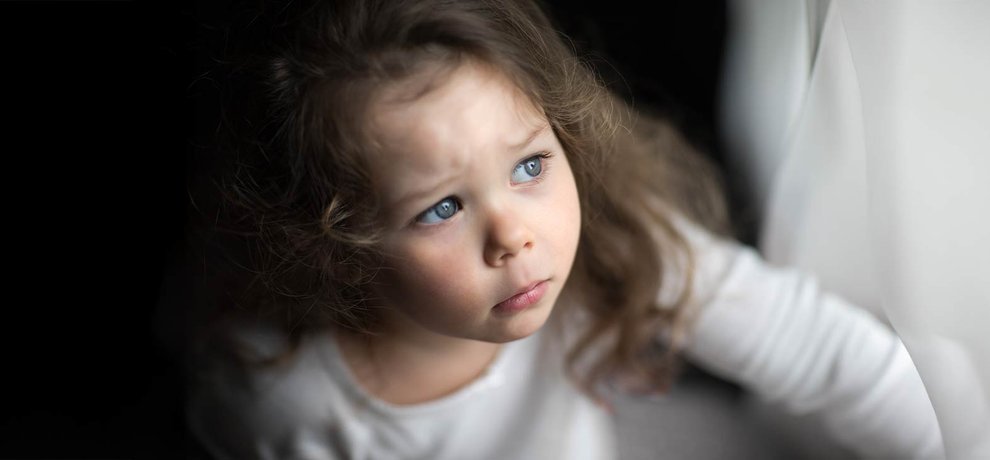 Enfant hypersensible au regard triste et pensif, sourcils froncés, vêtu de blanc